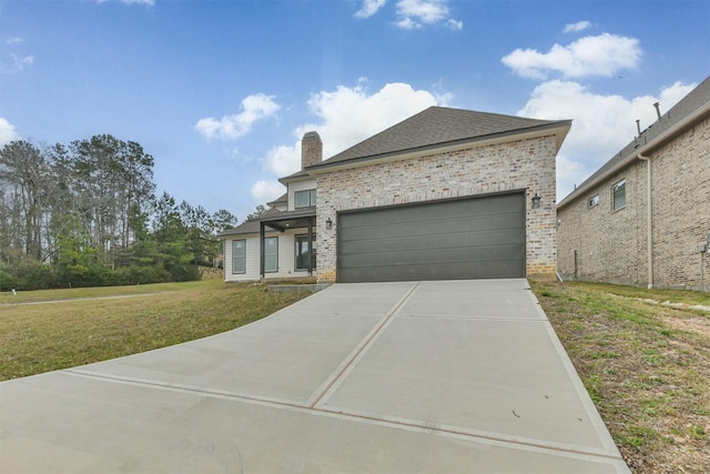 view of front of home with a garage, brick siding, driveway, a front lawn, and a chimney