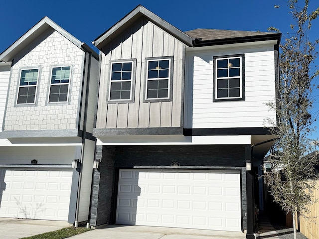 view of front of house featuring board and batten siding, driveway, a shingled roof, and a garage