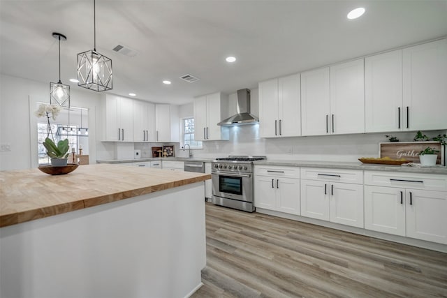 kitchen with light wood finished floors, visible vents, stainless steel range, butcher block counters, and wall chimney range hood