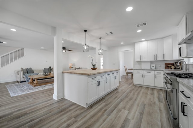 kitchen featuring white cabinetry, high end stainless steel range oven, visible vents, and light wood-style floors