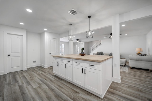 kitchen with visible vents, white cabinets, open floor plan, light wood-style floors, and wooden counters