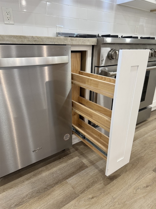 interior details featuring dishwasher, tasteful backsplash, and wood finished floors