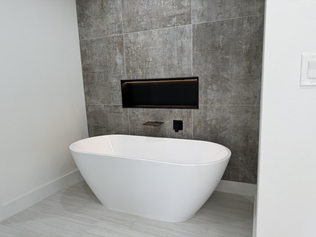 full bathroom featuring a soaking tub, baseboards, and tile walls