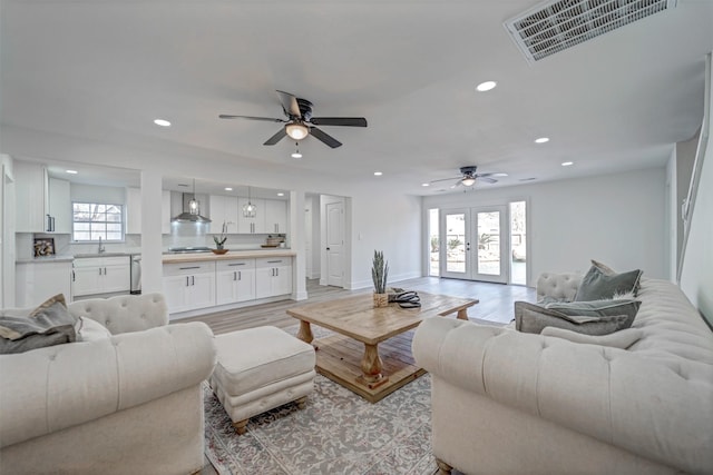 living area with visible vents, baseboards, light wood-style flooring, french doors, and recessed lighting