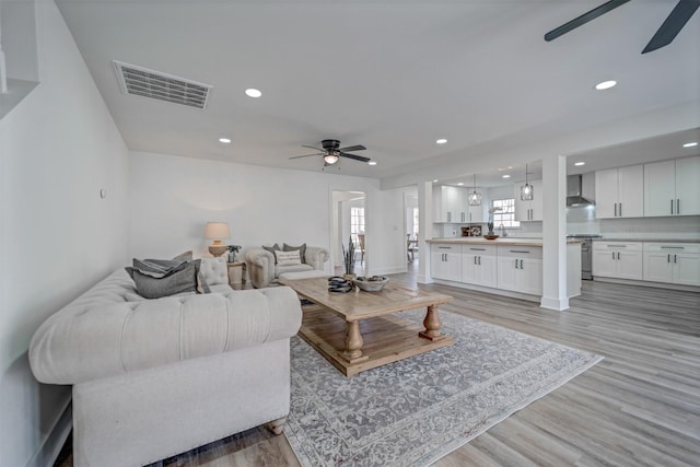 living area with light wood-style flooring, visible vents, ceiling fan, and recessed lighting