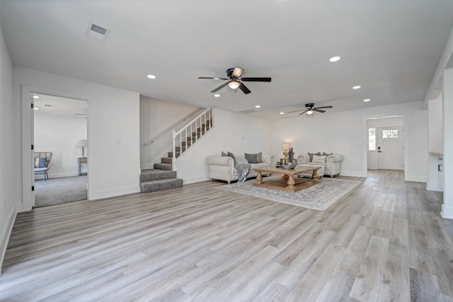 unfurnished living room featuring recessed lighting, baseboards, stairway, and light wood finished floors