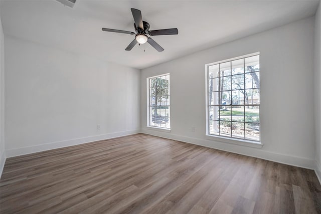 unfurnished room with wood finished floors, a ceiling fan, and baseboards