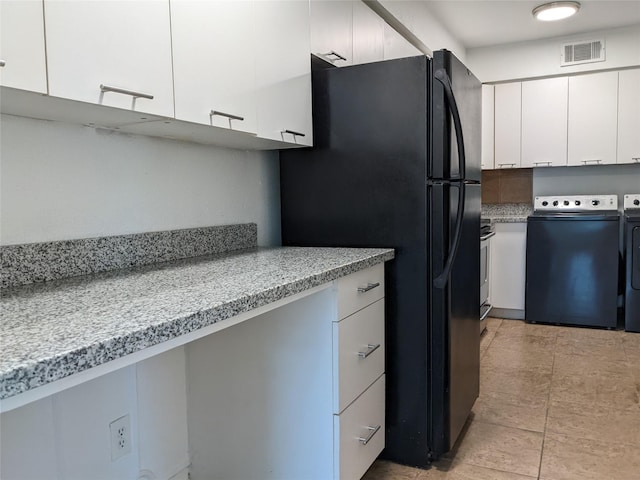 kitchen featuring visible vents, freestanding refrigerator, light countertops, washing machine and dryer, and white cabinetry