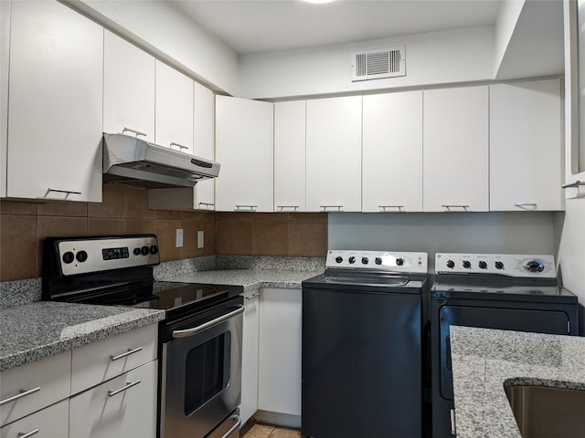 kitchen featuring washer and clothes dryer, visible vents, electric range, backsplash, and under cabinet range hood