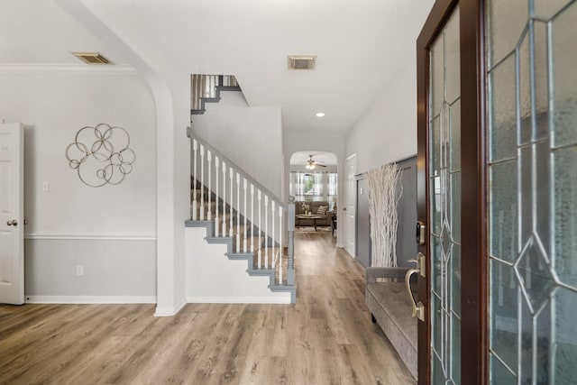 entryway with visible vents, arched walkways, baseboards, stairway, and wood finished floors