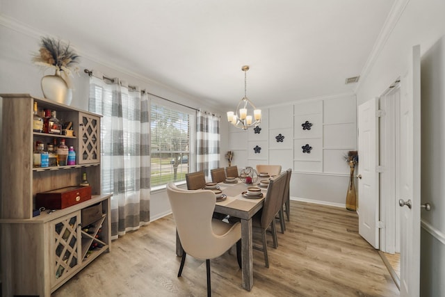 dining room with a notable chandelier, ornamental molding, visible vents, and light wood-style floors