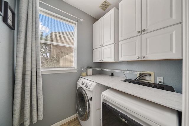 laundry area with cabinet space, visible vents, baseboards, and separate washer and dryer