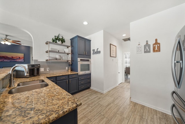 kitchen with light stone counters, wood finish floors, open shelves, stainless steel appliances, and a sink