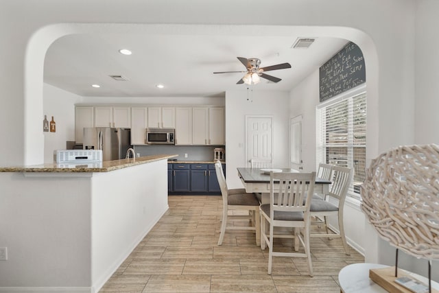 kitchen with visible vents, a ceiling fan, light stone counters, stainless steel appliances, and recessed lighting