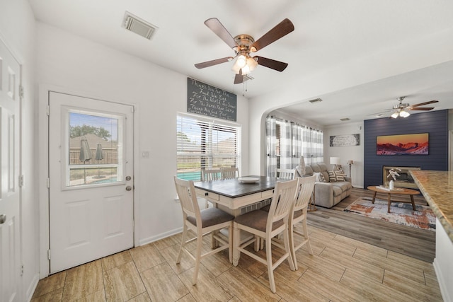 dining room with baseboards, visible vents, a ceiling fan, and wood finish floors