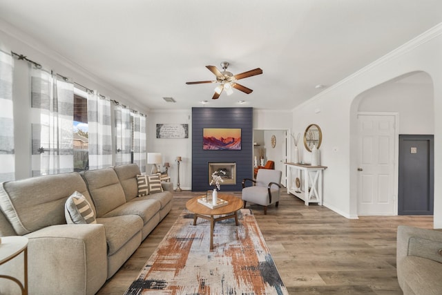 living room with arched walkways, a fireplace, and crown molding