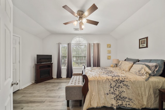 bedroom with vaulted ceiling, light wood-type flooring, visible vents, and baseboards