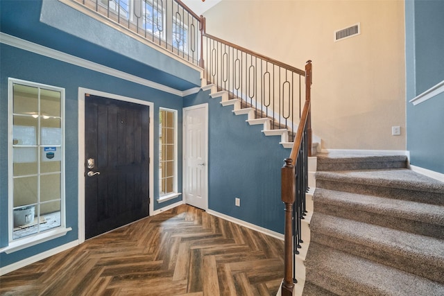 entrance foyer with baseboards, visible vents, stairway, and a high ceiling