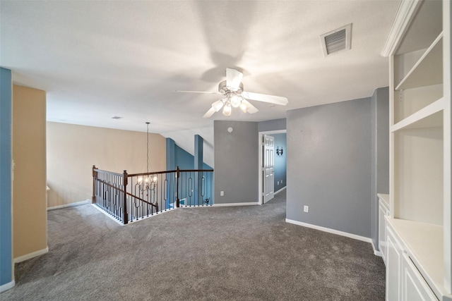 unfurnished room featuring ceiling fan with notable chandelier, carpet flooring, visible vents, and baseboards