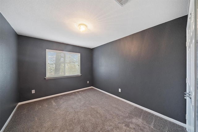 carpeted empty room featuring visible vents, a textured ceiling, and baseboards