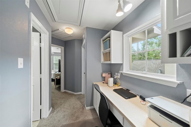 home office featuring light carpet, a wealth of natural light, attic access, and baseboards