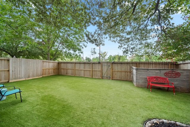 view of yard with a fenced backyard and a gate