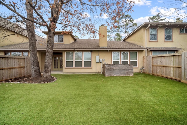 back of property featuring a fenced backyard, a chimney, french doors, and a yard