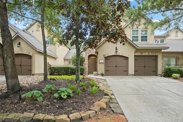 view of front of home with concrete driveway, a shingled roof, fence, and stucco siding