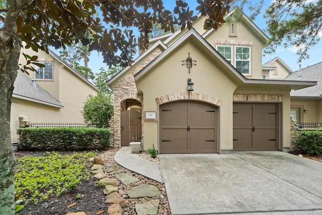 view of front of property featuring stone siding, fence, concrete driveway, and stucco siding