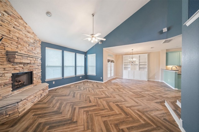 unfurnished living room featuring ceiling fan with notable chandelier, a fireplace, a sink, visible vents, and baseboards