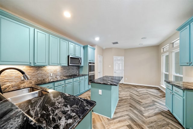 kitchen with visible vents, decorative backsplash, a kitchen island, stainless steel appliances, and a sink