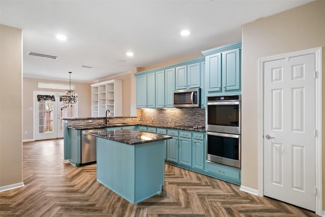 kitchen with a center island, blue cabinetry, stainless steel appliances, tasteful backsplash, and a peninsula