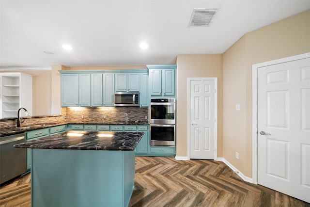 kitchen with appliances with stainless steel finishes, decorative backsplash, visible vents, and blue cabinets