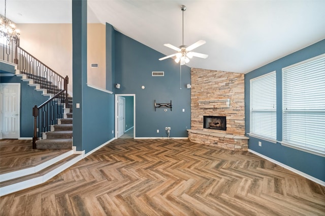 unfurnished living room featuring visible vents, a stone fireplace, high vaulted ceiling, baseboards, and stairs