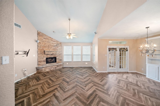 unfurnished living room with ceiling fan with notable chandelier, a stone fireplace, visible vents, and baseboards