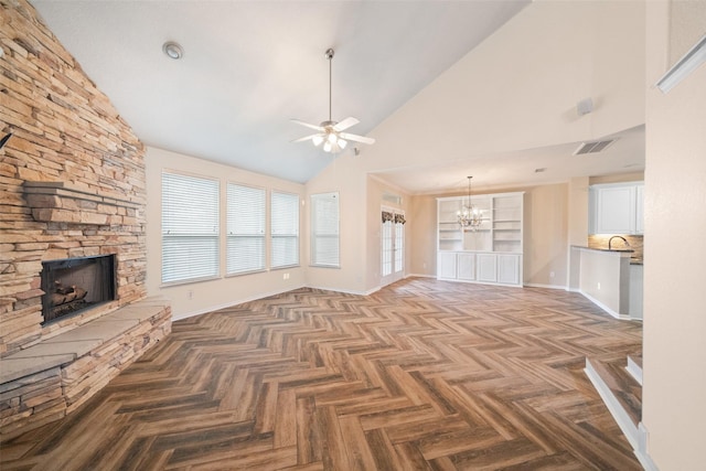 unfurnished living room with visible vents, a stone fireplace, high vaulted ceiling, baseboards, and ceiling fan with notable chandelier