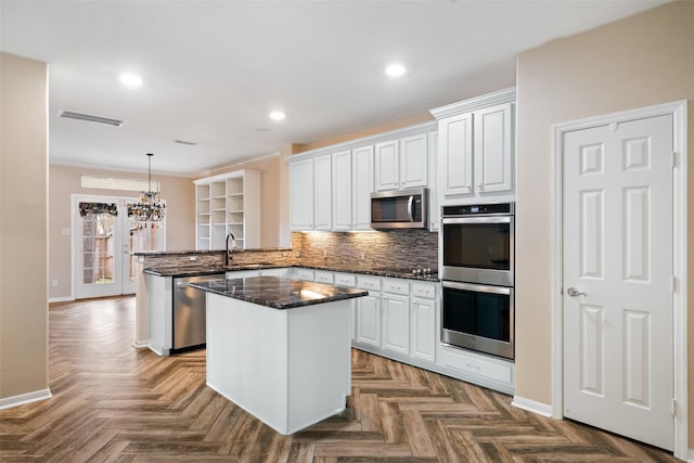 kitchen featuring a peninsula, white cabinetry, appliances with stainless steel finishes, and backsplash