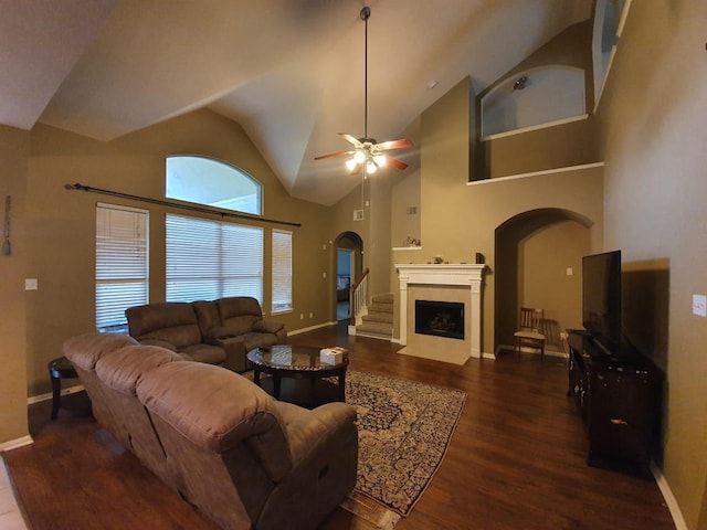 living area with baseboards, a fireplace with flush hearth, arched walkways, and wood finished floors