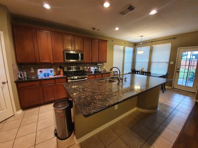 kitchen featuring light tile patterned floors, visible vents, brown cabinetry, stainless steel appliances, and a sink