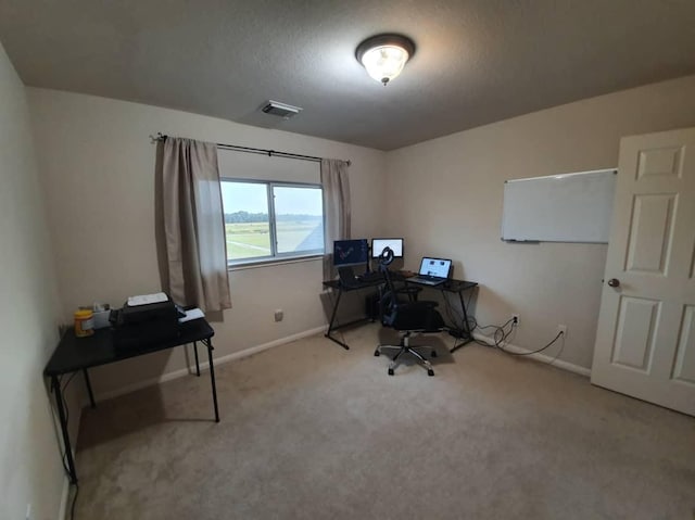 carpeted office space with visible vents, a textured ceiling, and baseboards