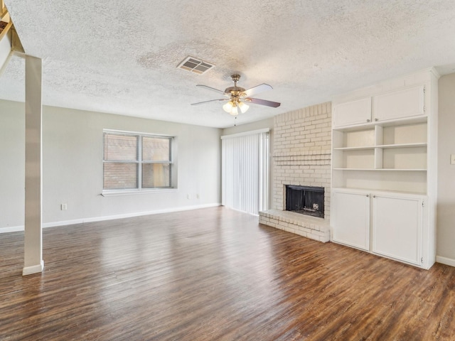 unfurnished living room featuring visible vents, dark wood-type flooring, a ceiling fan, a brick fireplace, and baseboards