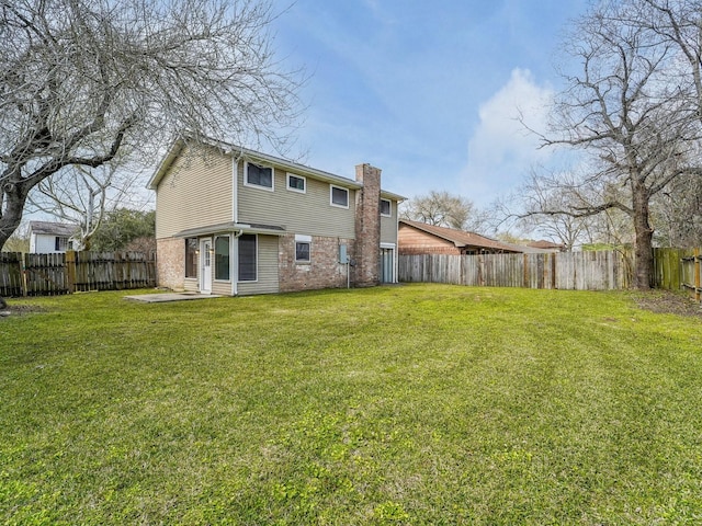 back of house with brick siding, a lawn, a chimney, and a fenced backyard