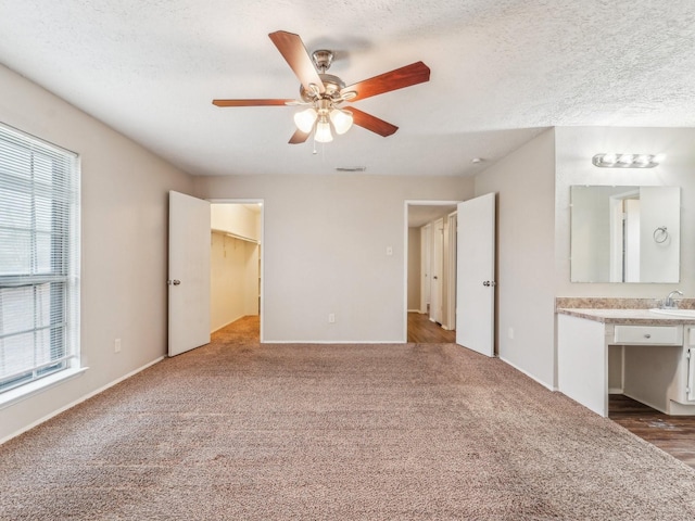 unfurnished bedroom with a textured ceiling, carpet, a sink, and visible vents