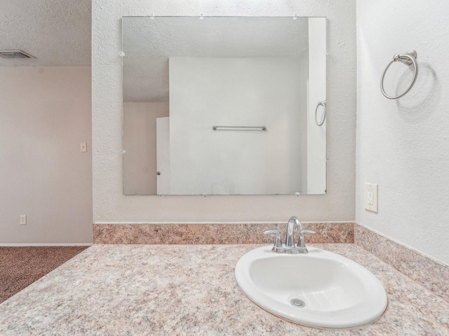 bathroom featuring visible vents, a textured wall, a textured ceiling, and vanity