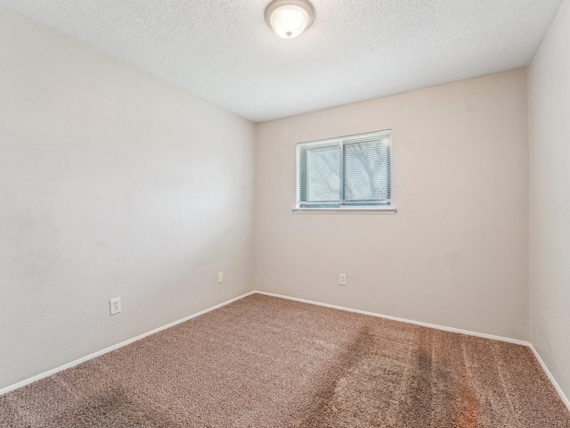 spare room featuring carpet flooring, a textured ceiling, and baseboards