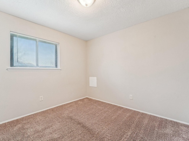 carpeted empty room featuring baseboards and a textured ceiling