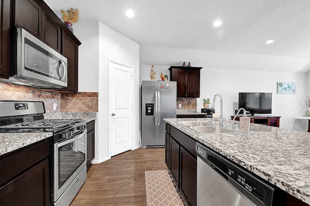 kitchen featuring dark brown cabinetry, tasteful backsplash, appliances with stainless steel finishes, dark wood-type flooring, and a sink