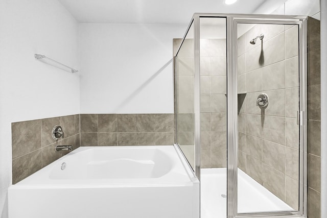 bathroom featuring a stall shower and a bath