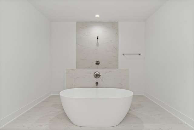 full bath featuring recessed lighting, marble finish floor, a soaking tub, and baseboards