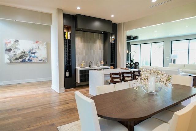 dining space featuring recessed lighting, baseboards, wet bar, and light wood-style floors